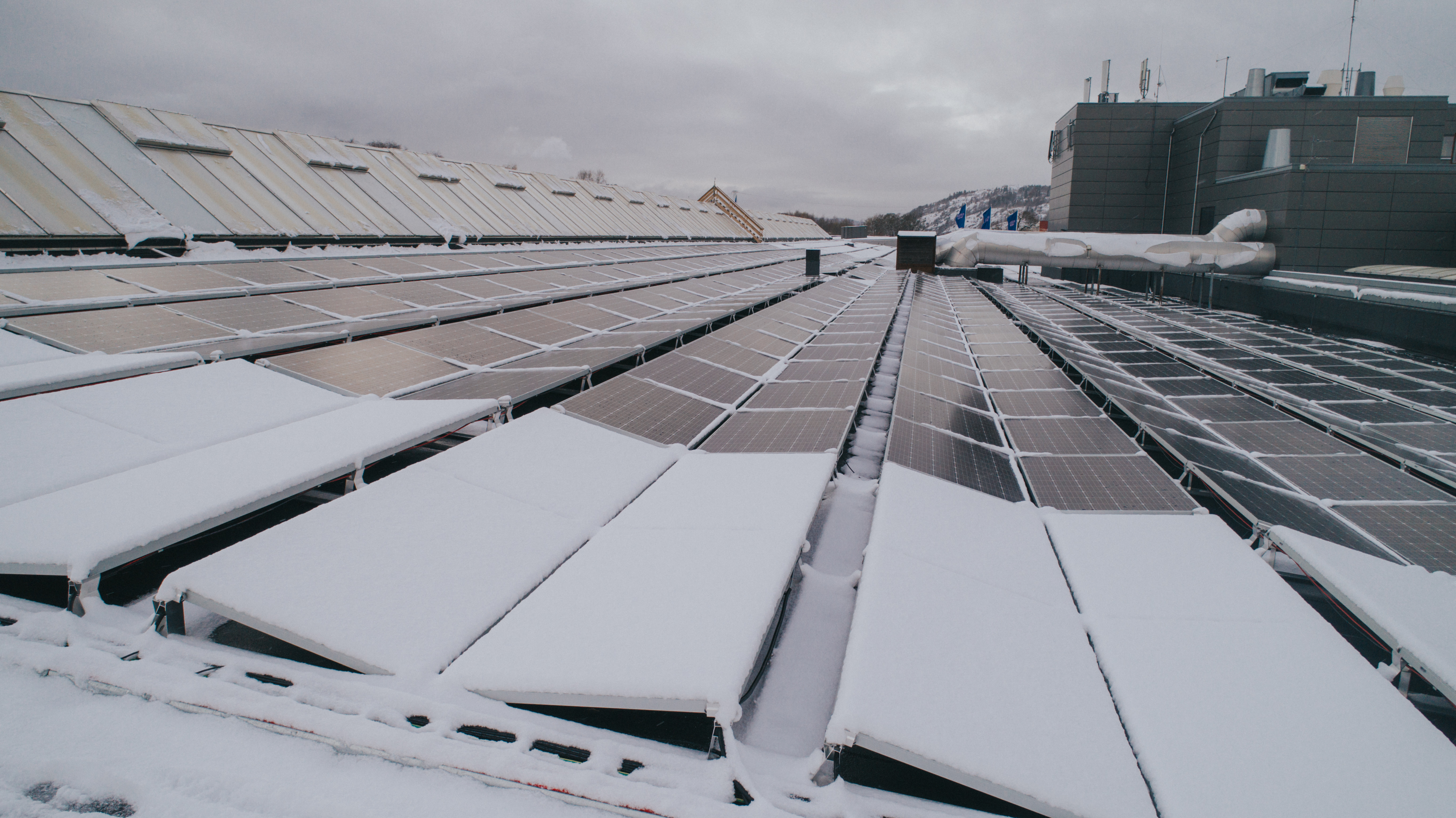 Solceller dekket av snø, på et industribygg tak